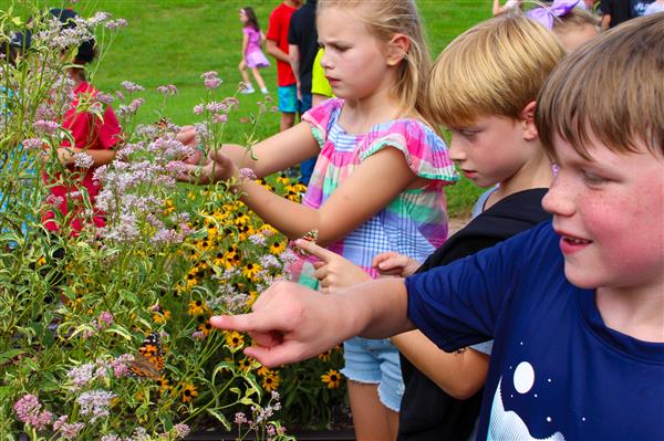 students in a flower garden with butterflies